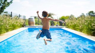 kid jumping into a blue pool