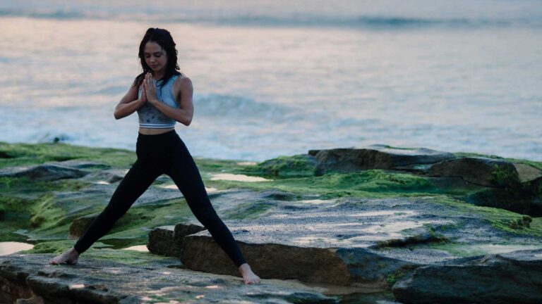 woman doing yoga on cliff above coast