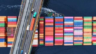 intermodal containers on barge passing under freeway bridge