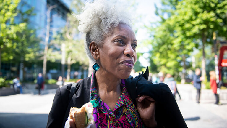 older black woman smiling and walking down street