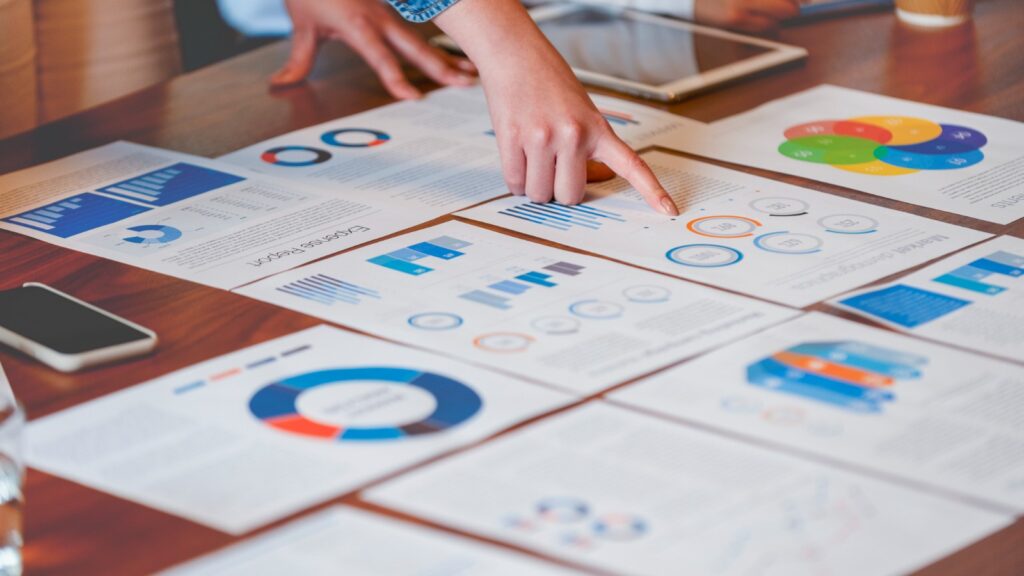 person pointing to sheets of data on desk
