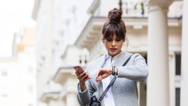 woman holding phone but looking at watch