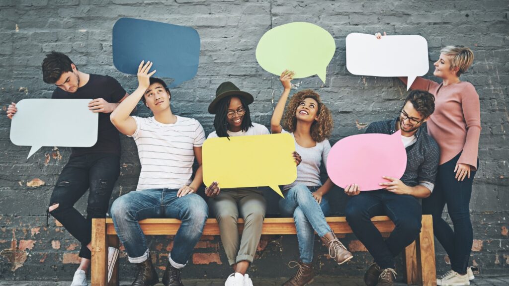 people on bench holding talk bubbles out of paper