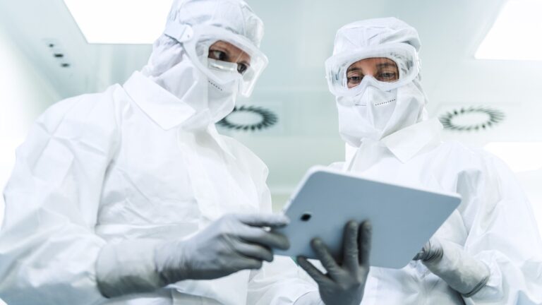 2 people in anti static suits looking at tablet