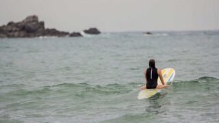 A photograph of a woman heading out to surf