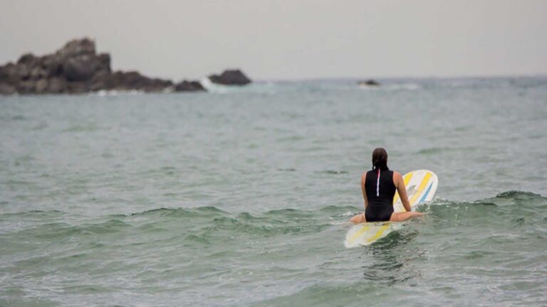 A photograph of a woman heading out to surf