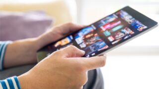 A person using a tablet to decide which streaming TV app to use