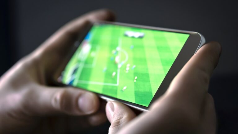 Man streaming soccer game live, video replay or highlights online with smart device.