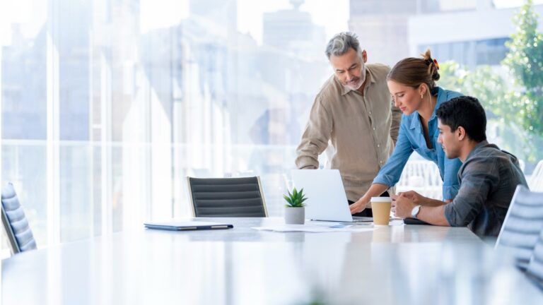 A Hispanic business leader discussing work with 2 employees