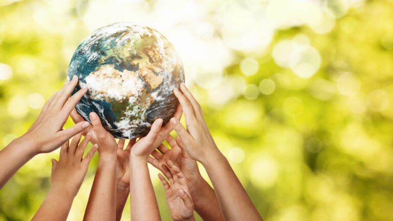 Group of children holding planet earth over defocused nature background