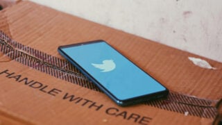 Phone displaying Twitter atop of a box that reads Handle With Care
